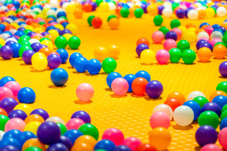 A vibrant scene of colorful plastic balls scattered across a bright yellow play surface.の写真素材