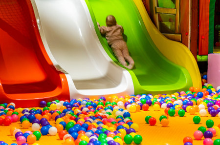 A playful toddler climbing a colorful slide surrounded by a vibrant ball pit.の写真素材