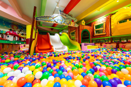 A spacious indoor playground with colorful ball pits and vibrant slides for endless fun.の写真素材