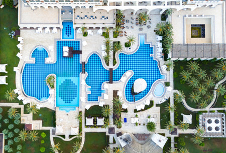 Aerial view of a luxury resort with a uniquely designed pool, lush gardens, and elegant sunbathing areasの写真素材