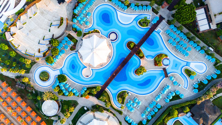 Aerial view of a luxury resort with a wave-shaped pool and elegant sunbathing areasの写真素材