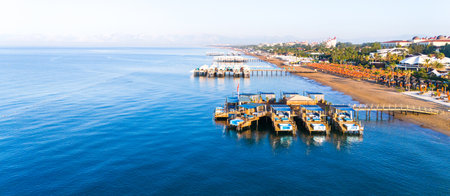 Panoramic aerial view of a luxury beach resort with wooden piers over the calm sea.の写真素材