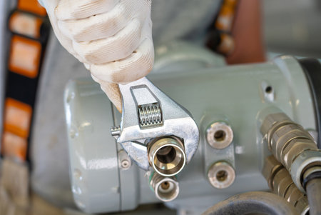 A close-up of a mechanic using an adjustable wrench during equipment maintenance.の写真素材