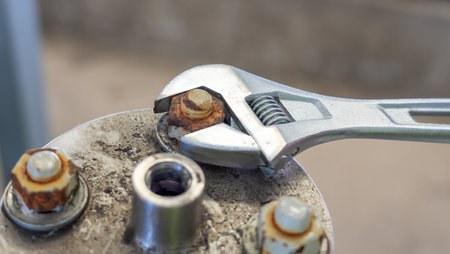 Adjustable wrench used to loosen a rusty bolt on a metal surface.の写真素材