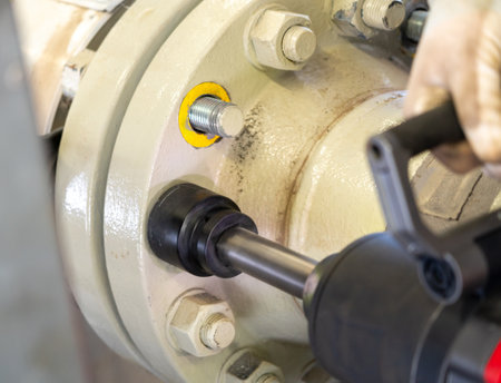 Close-up of an electric impact wrench loosening bolts on a pipeline flange.の写真素材