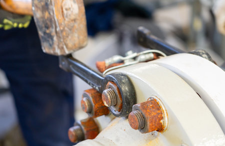 Warning: Improper use of a hammer with a wrench on an industrial flange connection, highlighting safety violationsの写真素材