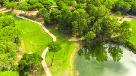 Aerial view of a golf course with a scenic pond, winding path, and lush greeneryの写真素材