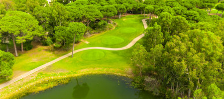 Aerial view of a golf course with a scenic pond, lush greenery, and winding pathsの写真素材