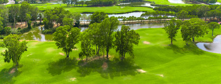Panoramic view of a golf course with water features, sand traps, and scattered treesの写真素材