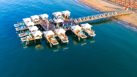 Aerial view of a luxury beachfront resort with private overwater cabanas on a wooden pier.の写真素材