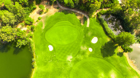 Aerial view of a golf course featuring a putting green with a hole, sand bunkers, and surrounding pondsの写真素材