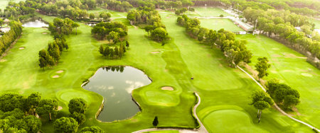 A panoramic aerial view of a golf course with a scenic pond and lush greenery.の写真素材