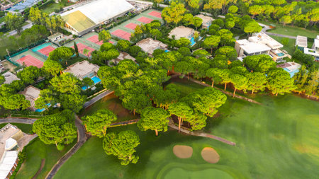 Aerial view of a luxury resort with golf course, tennis courts, and private villas among lush greeneryの写真素材