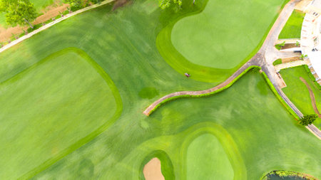 Aerial view of a golf course with a bridge, sand bunker, and clubhouse surroundingsの写真素材