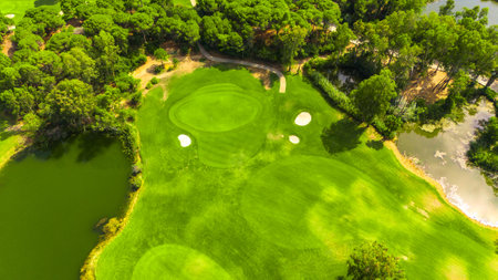 Aerial view of a golf course with putting greens, sand bunkers, and water hazards surrounded by treesの写真素材