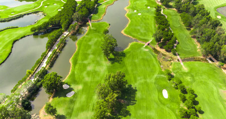 Aerial view of a golf course with water hazards, fairways, sand bunkers, and connecting bridgesの写真素材