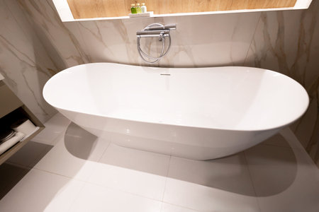 A modern freestanding white bathtub in a clean and elegant luxury bathroom interior