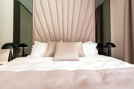 A cozy modern hotel bed with soft pillows, elegant headboard and stylish interior design