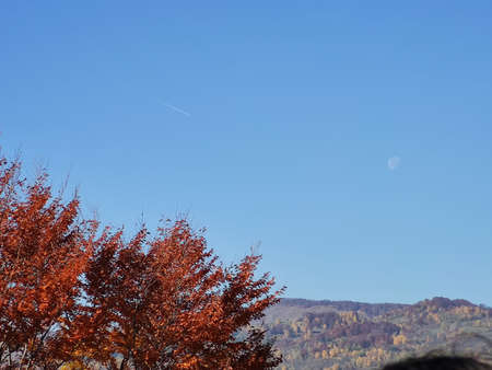 Autumn in the mountains. The moon in the blue sky.の写真素材