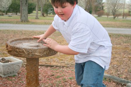 Young boy fixing the birdbathの写真素材
