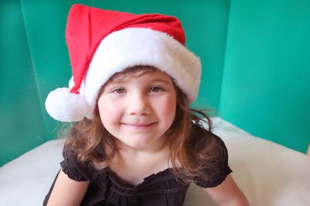 Cute little girl sitting wearing a santa hatの写真素材