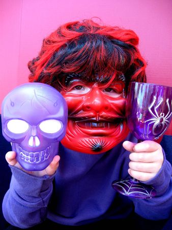 Halloween child in devil mask holding a skullの写真素材