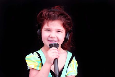 Cute little girl holding microphone and singingの写真素材