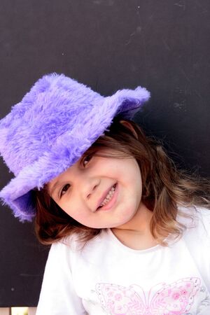 Little girl in purple hat smilingの写真素材