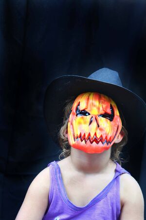 Girl in hat and pumpkin maskの写真素材