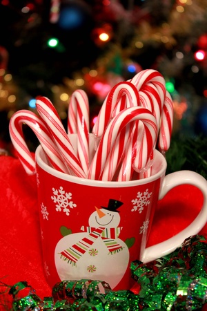 Christmas cup with candy caes inside and tree lights behindの写真素材