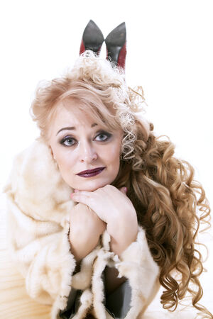 curly-haired woman in a fur coat lying on the parquet on white backgroundの写真素材