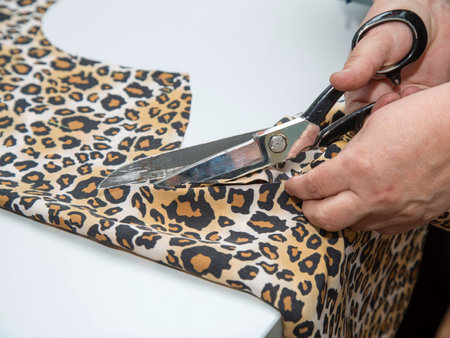dressmaker cutting leopard fabric.Close up