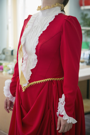 close-up of fashion designer adjusting red dress on modelの写真素材