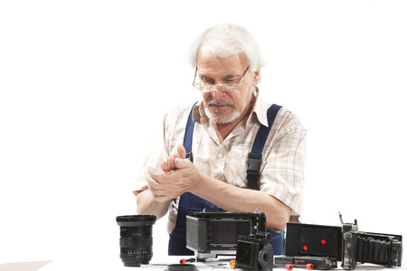 Male repairing an old camera at his workplace on white backgroundの写真素材