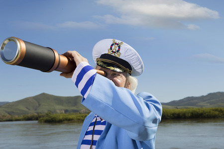 The captain on vacation looking through a telescope into the distanceの写真素材