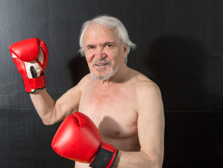 Close-up portrait of an elderly boxer on a dark backgroundの写真素材