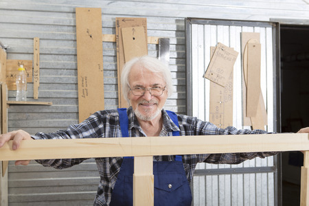 Worker using saw machine to make furniture at carpenters workshop. Handmade business at small furniture factory.の写真素材