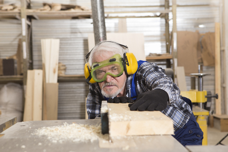 Worker using saw machine to make furniture at carpenters workshop. Handmade business at small furniture factory.の写真素材