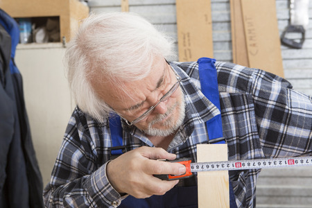 Worker using saw machine to make furniture at carpenters workshop. Handmade business at small furniture factory.の写真素材
