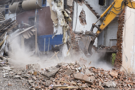 The destruction of the walls of the old building and the cleaning of construction debris with a bucket of an excavator.の写真素材