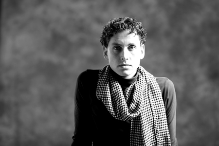 Charming young man with curly hair and a scarf around his neckの写真素材