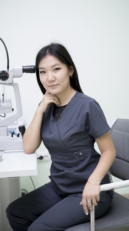 Asian girl ophthalmologist at her workplace working with deviceの写真素材