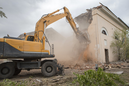 The destruction of the walls of the old building and the cleaning of construction debris with a bucket of an excavator.の写真素材