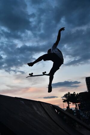 Skateboarding as extreme and fun sport. Skateboarder doing a trick in a city skate park.の写真素材