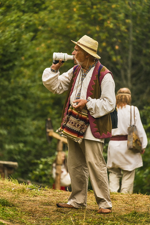 Urych, Ukraine - August 6,2016: Tustan Medieval Culture Festival in Urych, Western Ukraine, on August 6, 2016 .Participant of the festival in ethnic clothes drinking yogurt after the show.のeditorial素材