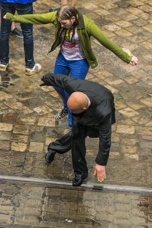 Lviv, Ukraine - May 2,  2016: Celebration pouring water on Monday after Easter by the town hall. Bald man dancing among a people.のeditorial素材