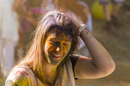 Lviv, Ukraine - August 28, 2016: Cheerful girl in color powder caress her hair  during the festival of color in a city park in Lviv.のeditorial素材