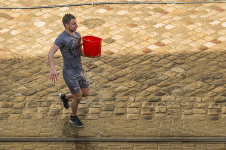 Lviv , Ukraine - April 09 2018:  Ð¡elebrations  Wet Monday, a Ukrainian Christian tradition celebrated on the first day after Orthodox Easter. Young  man is preparing to pour water on the townspeople near the town hall. Lviv, Ukraine.のeditorial素材