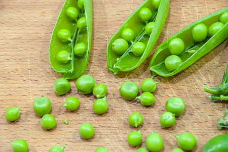 Fresh pods of sweet green peas in basket, on wooden boardの写真素材