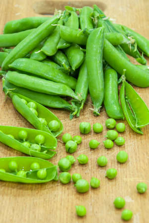 Fresh pods of sweet green peas in basket, on wooden boardの写真素材